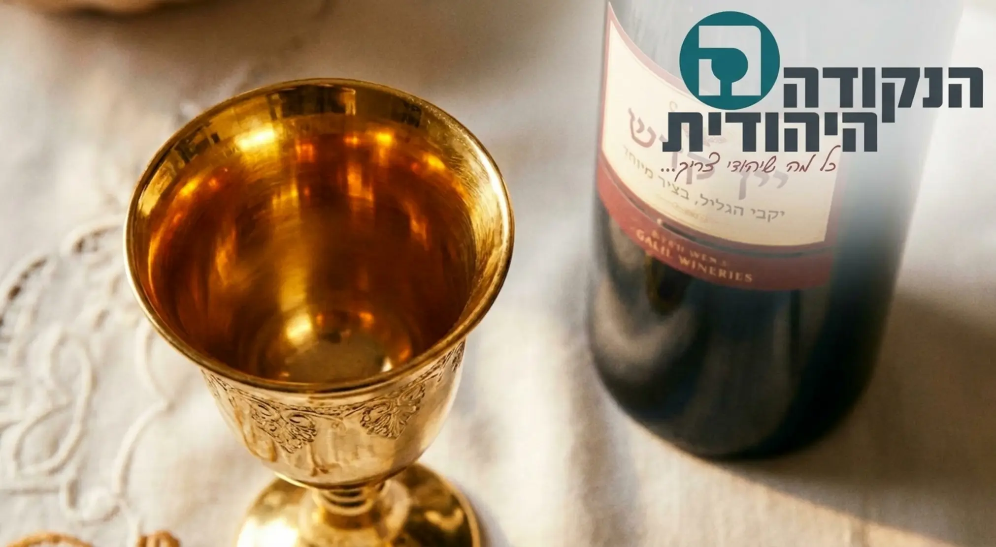 תמונה תקריב (קלוז אפ) איכותית המציגה את פנים הגביע המוזהב בוהק באור חם, ולצידו בקבוק יין אדום יוקרתי על מפת שבת לבנה וצחה